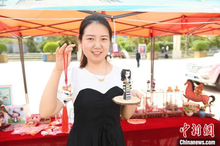 圖為游客展示在非遺工坊購買的玩偶。　戴文昌 攝