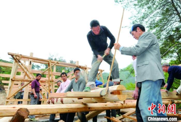 資料圖為木拱廊橋建造過程中，匠人們正在“搭屋架”?！↓徑?攝