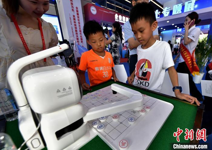 圖為前來參觀的小朋友在和象棋機器人對弈?！埍?攝
