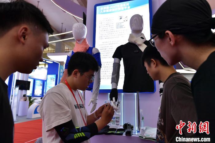 圖為參觀者在展會上體驗具有人體健康監(jiān)護預警功能的衣服?！埍?攝