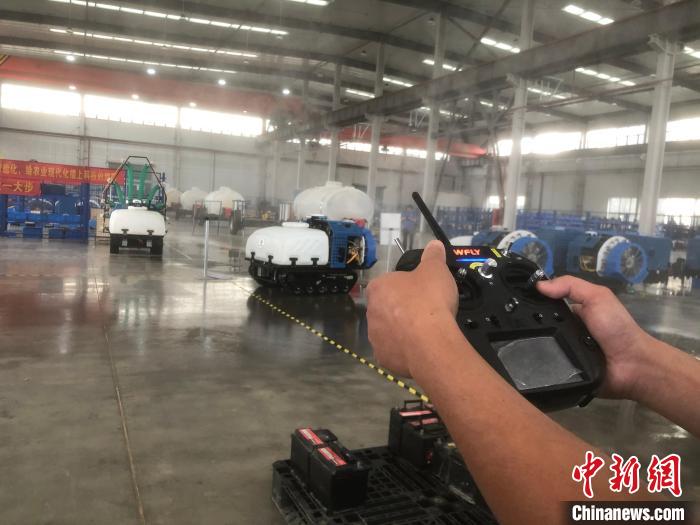 一名工人拿著遙感器，指揮機(jī)器人進(jìn)行“農(nóng)藥”噴灑作業(yè)。　劉林 攝