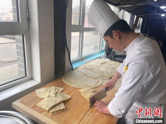 陳經(jīng)偉將餅切成長(zhǎng)條備用。　楊靜 攝