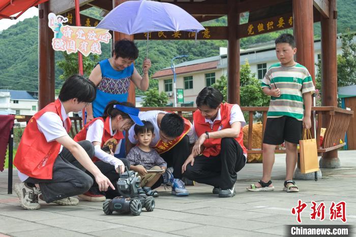 圖為學(xué)子們指導(dǎo)小朋友使用機(jī)器人?！￡愐圾Q 攝