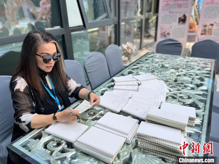 連玲玉在孩子們的空白筆記本上簽名留言?！≈鞎苑f 攝