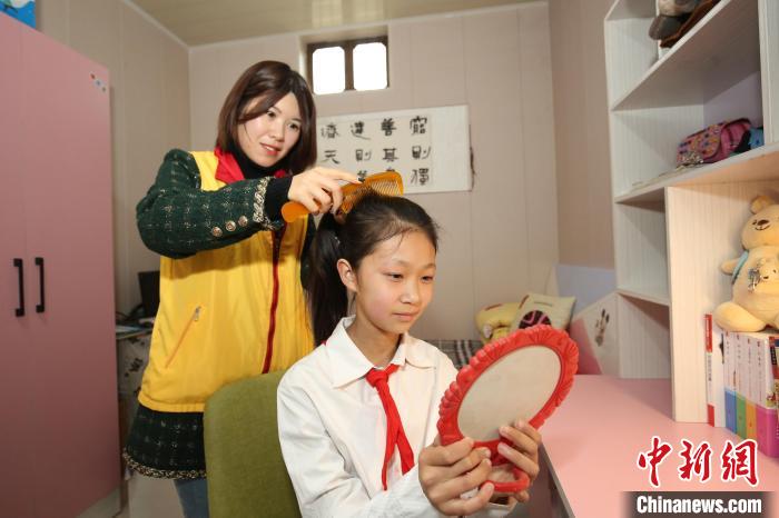 鄒城市“希望小屋”愛(ài)心媽媽志愿服務(wù)隊(duì)志愿者為兒童扎辮子?！⊥跹├?攝