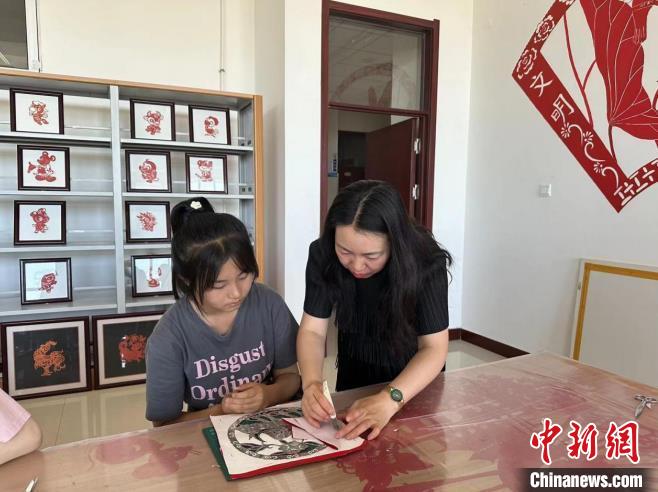圖為胡穎指導學員學習剪紙藝術(shù)?！罹靶?攝