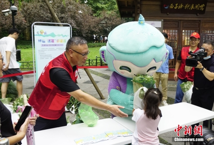 杭州亞運會吉祥物“琮琮”“宸宸”“蓮蓮”在浙江杭州西湖畔參加蓮蓬荷葉義賣活動，圖為亞運會吉祥物“蓮蓮”將分包好的蓮蓬、荷葉交給顧客。<a target='_blank' href='/'>中新社</a>發(fā) 王瓊苓 攝
