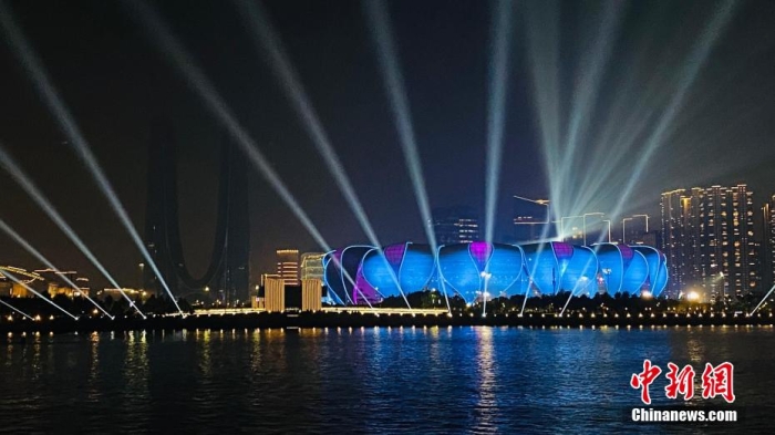 18日，杭州亞運(yùn)會(huì)開幕式演練舉行。隨著亞運(yùn)臨近，夜間的杭州錢塘江畔旖旎多彩，杭州亞運(yùn)會(huì)主體育場(chǎng)——杭州奧體中心體育場(chǎng)融入璀璨江景，諸多游客登船共享兩岸亞運(yùn)主題燈光秀。圖為燈光璀璨的杭州奧體中心體育場(chǎng)。錢晨菲 攝