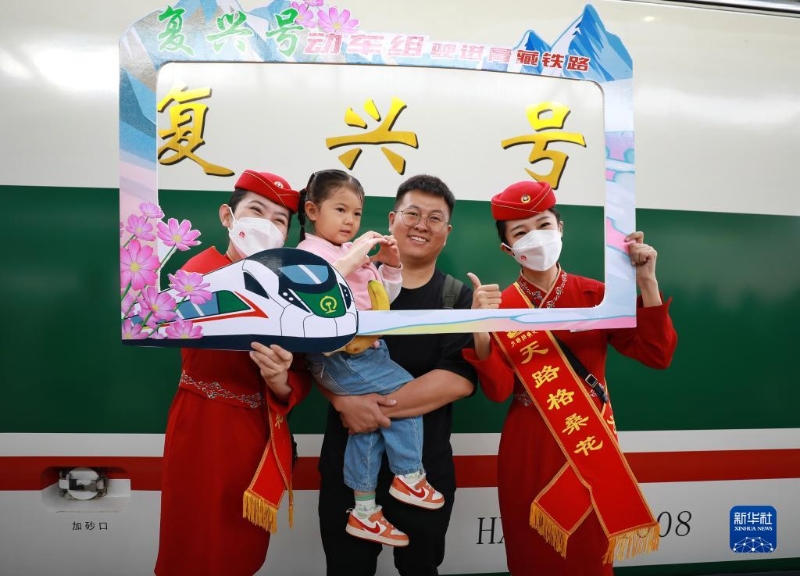 2023年7月1日，乘客與乘務(wù)人員在西寧至格爾木動車組首發(fā)列車前合影留念。（圖源：新華社）